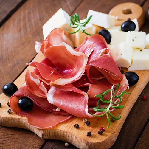 Prosciutto served with artisan cheese, olives, and fresh rosemary on a wooden charcuterie board.